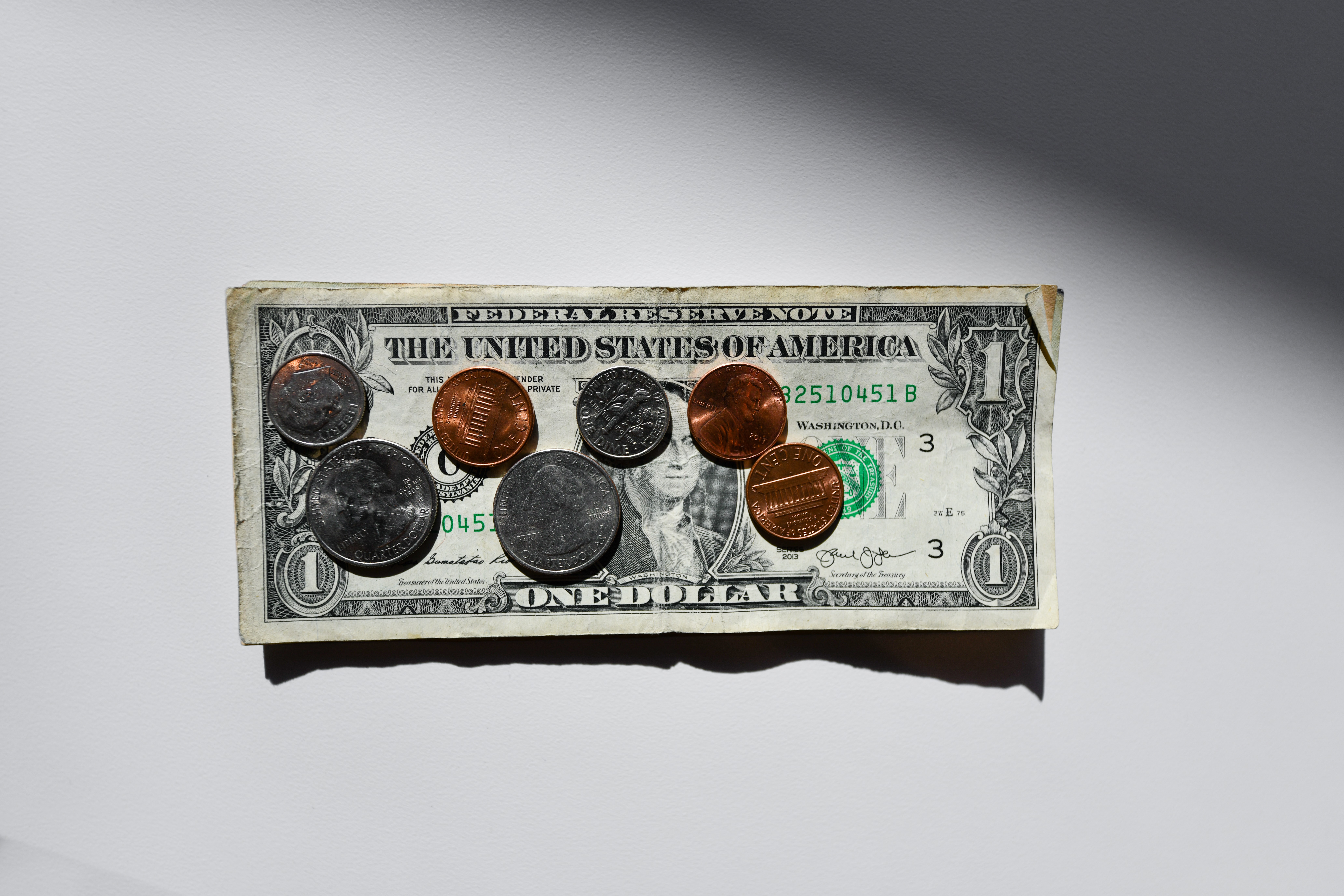 A dollar bill and various coins on a white background